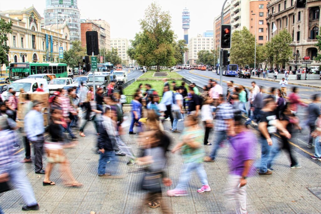 crowd of people crossing a busy street crosswalk in the city of Santiago, Chile in South America