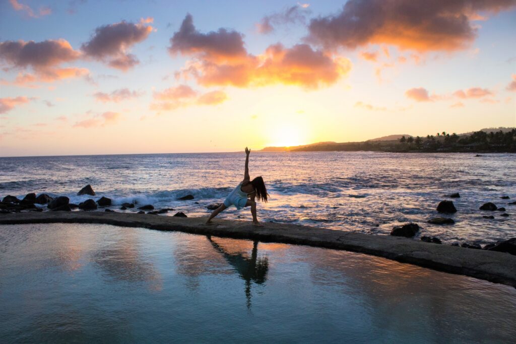 woman doing yoga at sunset on a beach