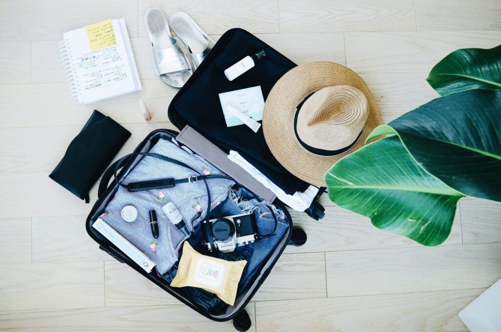 Open packed luggage with a camera and straw hat.