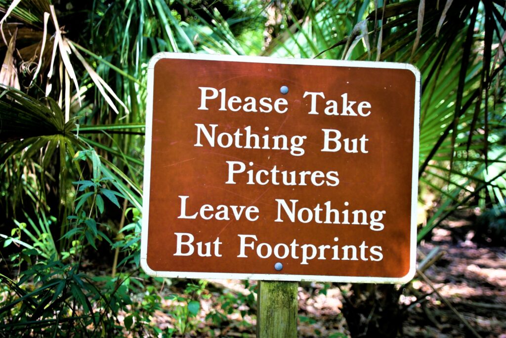 Sign in a forest reading “please take nothing but pictures, leave nothing but footprints”