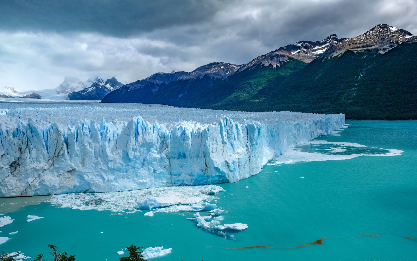 Large glacier in clear blue water with mountain in the background in Patagonia