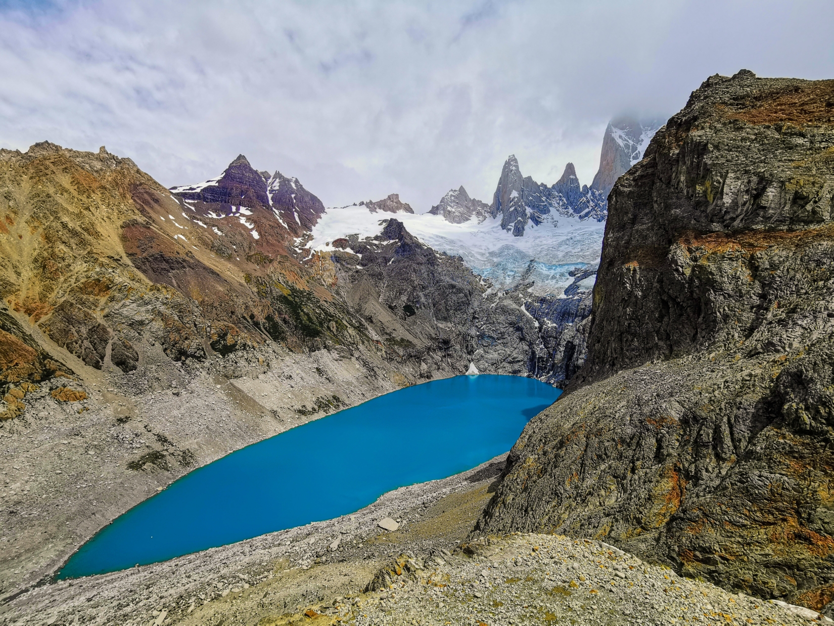 Dark blue lake surrounded by rocky snow-covered mountains