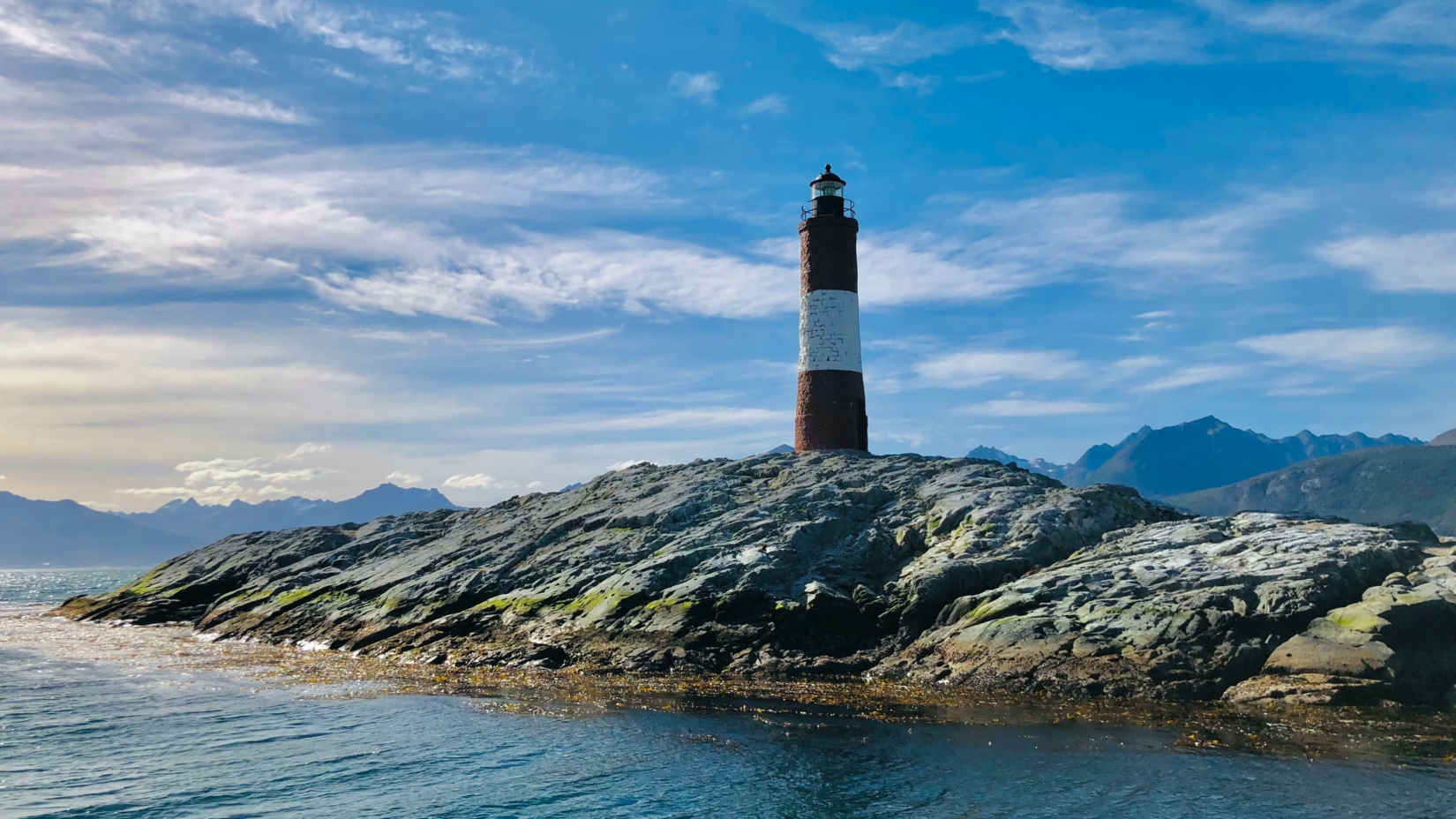 Lighthouse sitting on top of an island of rock in body of water