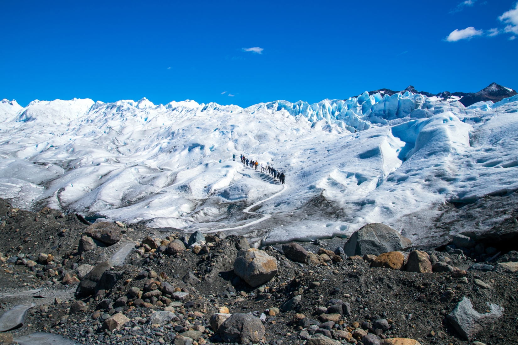 Line of trekkers walking up a glacier