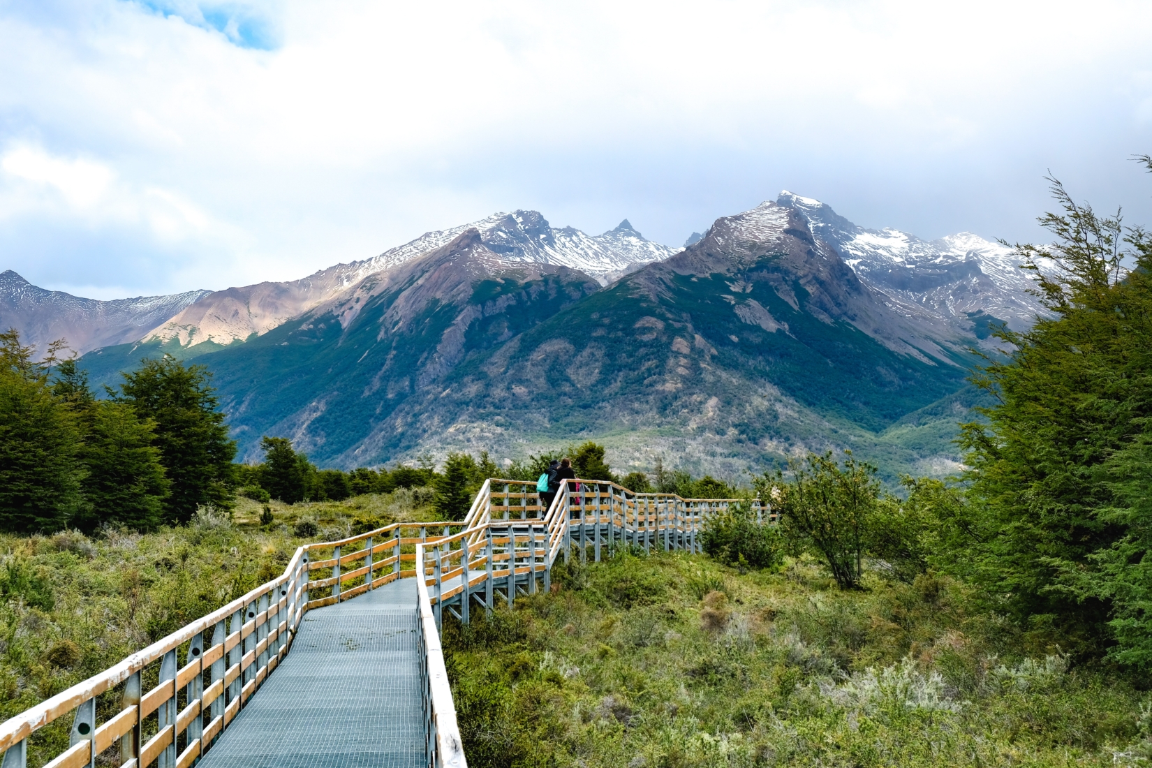 Walking bridge leading to mountain through shrubbery