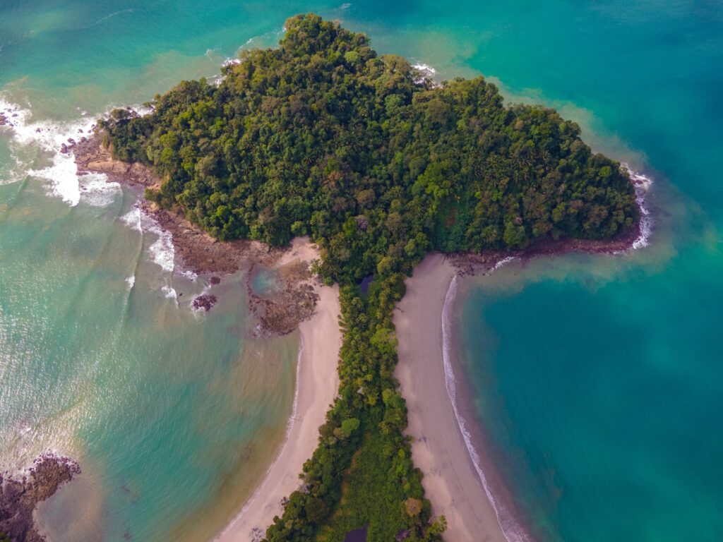 Mushroom-shaped peninsula filled with dense greenery with beaches outlining the stalk and turquoise waters surrounding the cutout