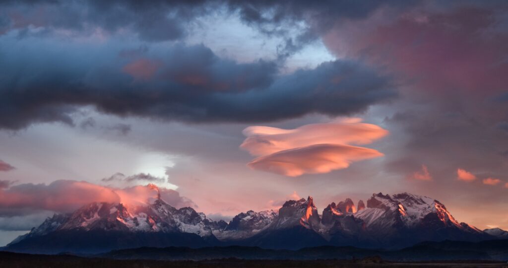 Sunset over the mountains in Torres del Paine, Patagonia. A unique cloud formation lingers in the center of the frame.